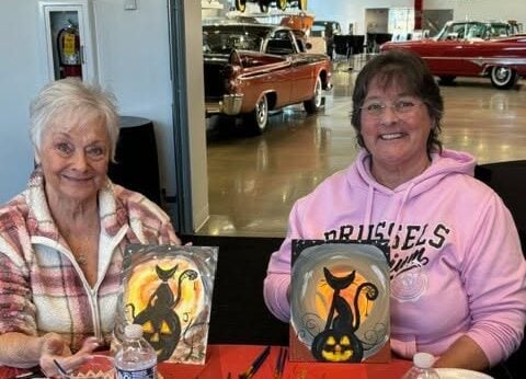 Two women showing their artwork
